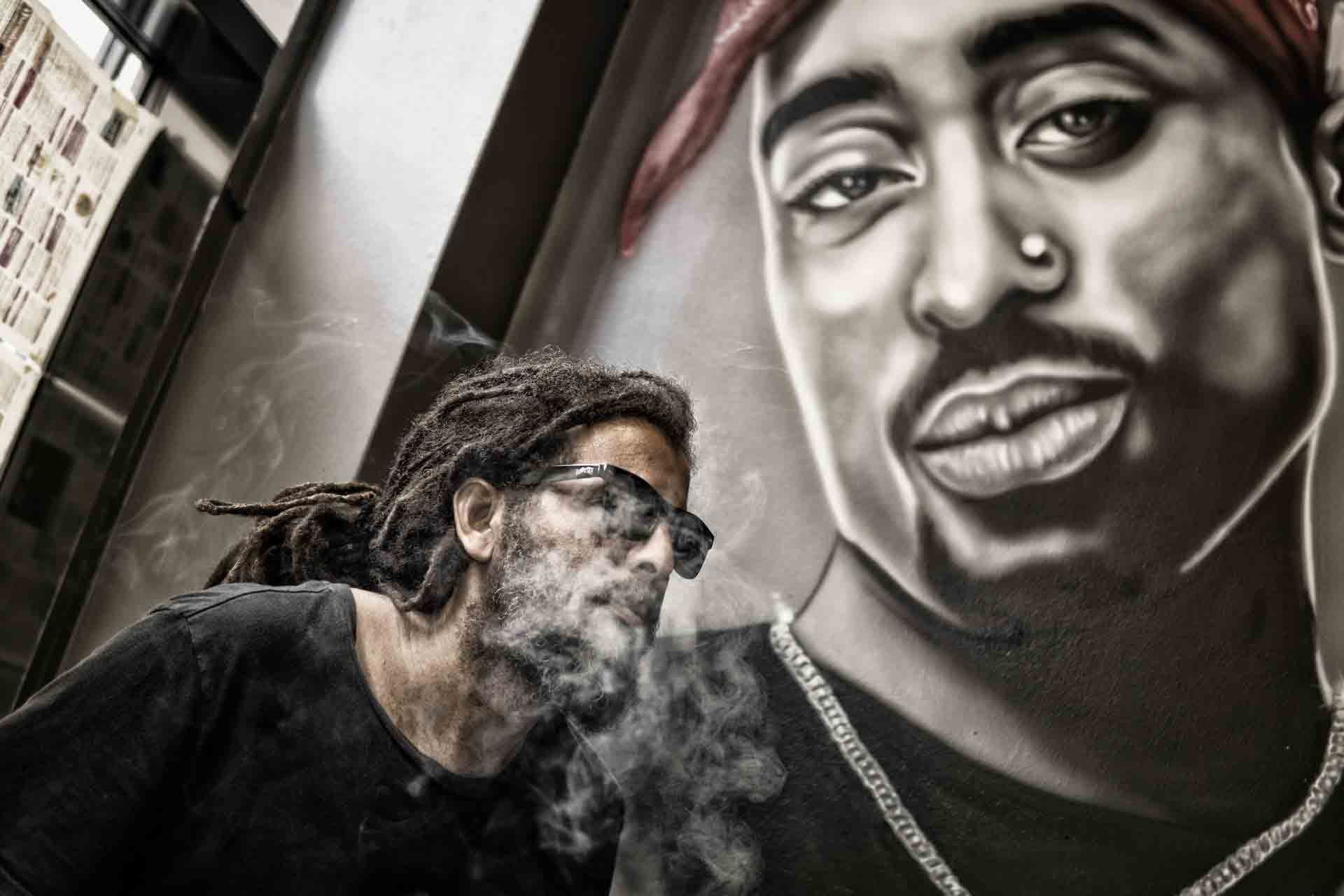 man-with-dreadlocks-and-sunglasses-poses-near-tupac-shakur-802195